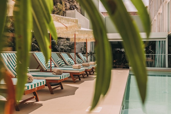 Una piscina techada, una piscina al aire libre, sombrillas