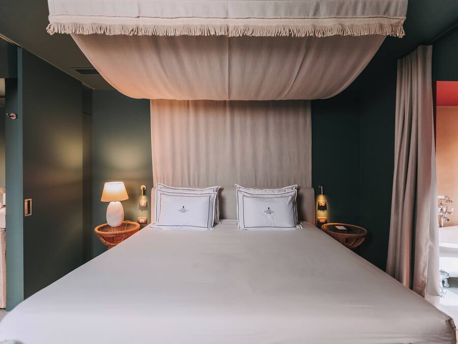 A large bed with two pillows, a bedside lamp, and a nightstand with a bottle.