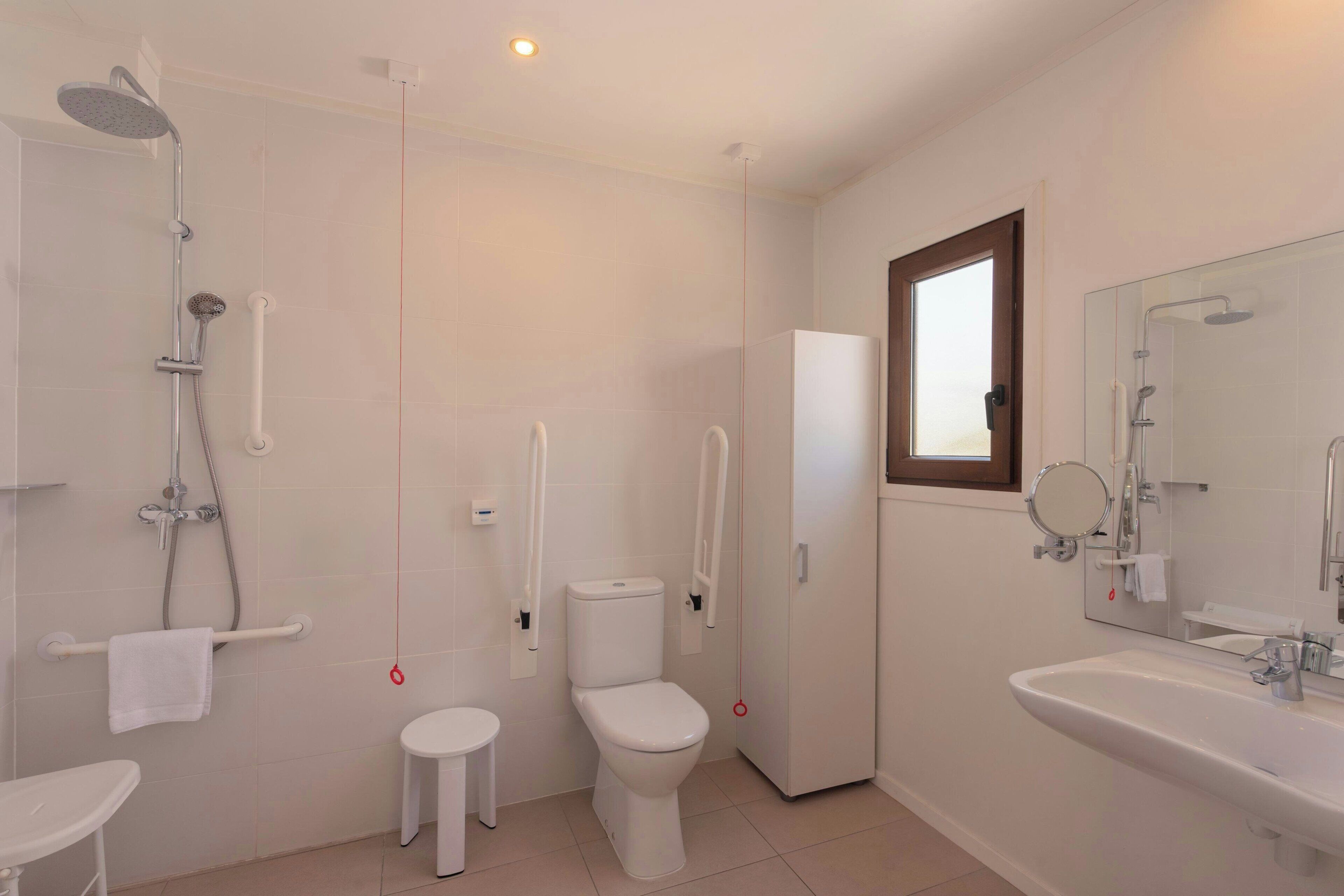 Un baño moderno con ducha, inodoro, lavabo y espejo.