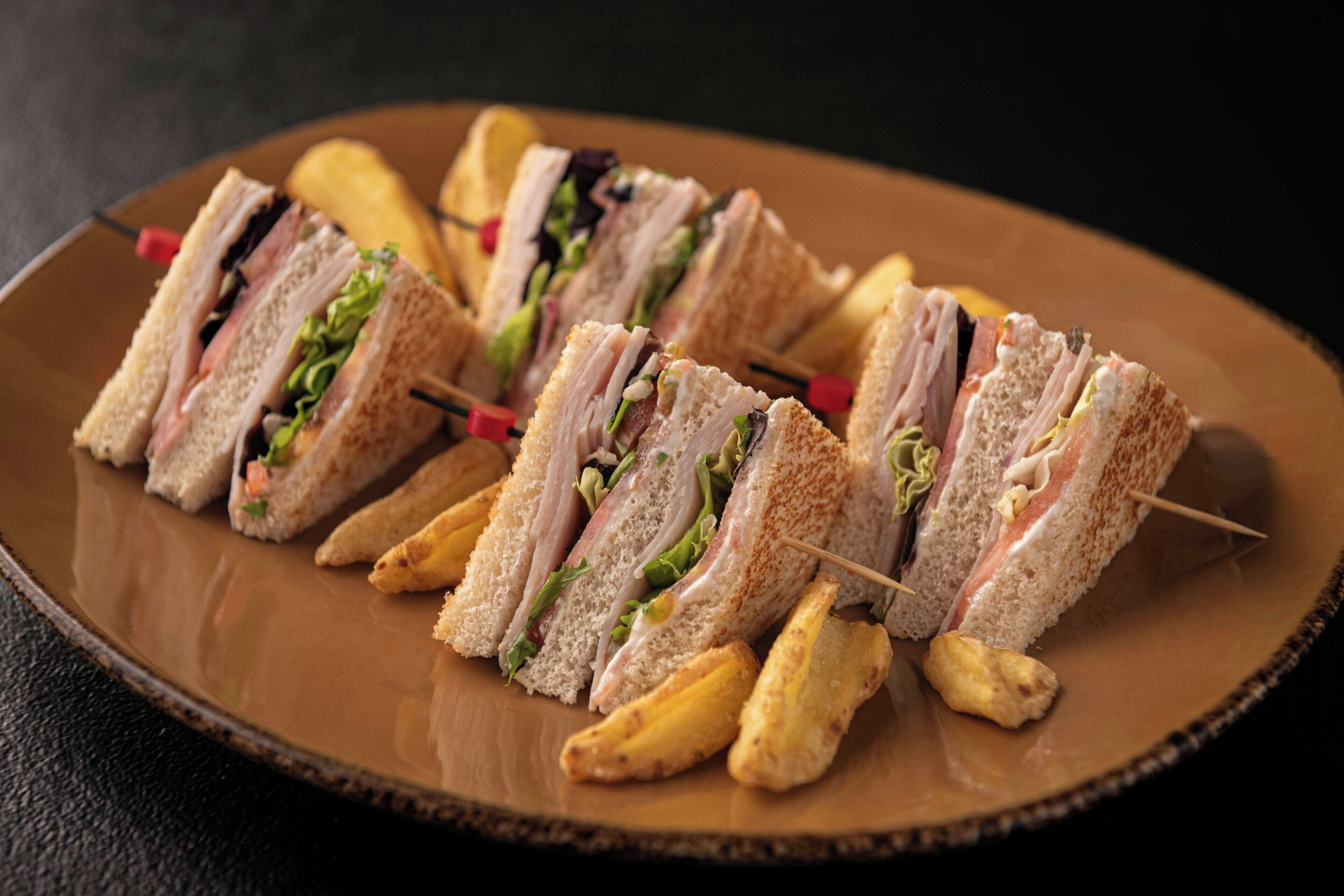 A plate with several sandwiches and fries.
