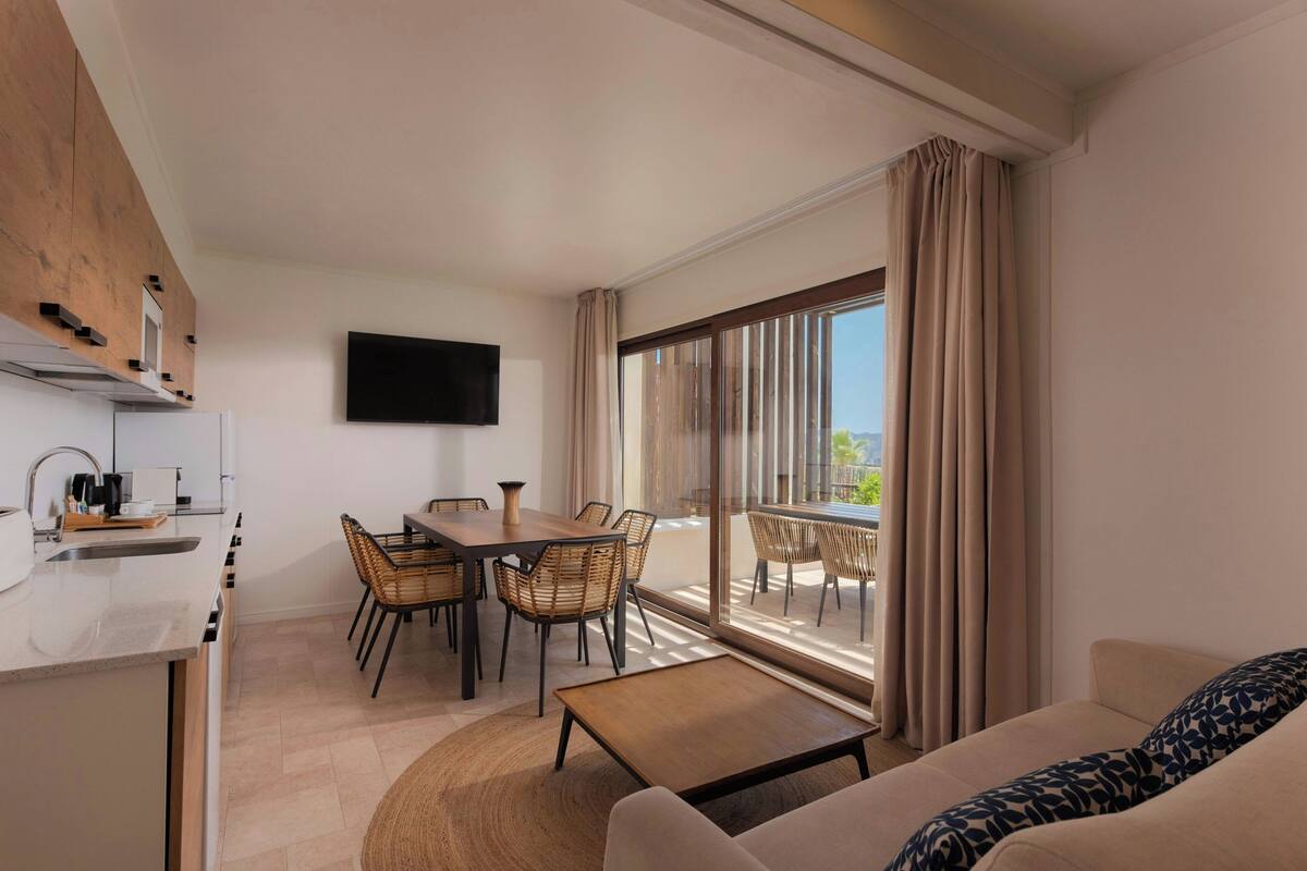 Habitación de hotel moderna con cocina, comedor y balcón con vistas.
