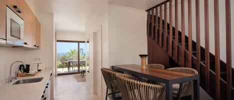 A modern kitchen with a built-in microwave, a sink, and a dining area with a wooden table and wicker chairs.