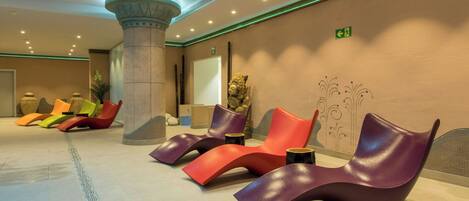 Un lobby moderno con una fila de sillones coloridos, un pilar grande y una pared decorativa.