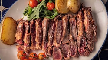 A plate of sliced meat, potatoes, and cherry tomatoes.