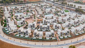 Un complejo residencial moderno con varias edificaciones de dos pisos, dispuestas en un círculo alrededor de un espacio verde central.