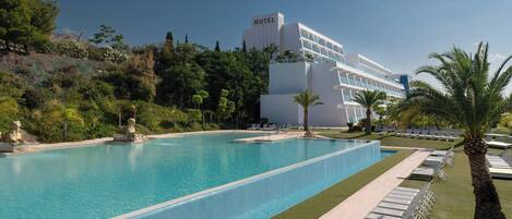 Un hôtel doté d’une grande piscine, de chaises longues et de palmiers.