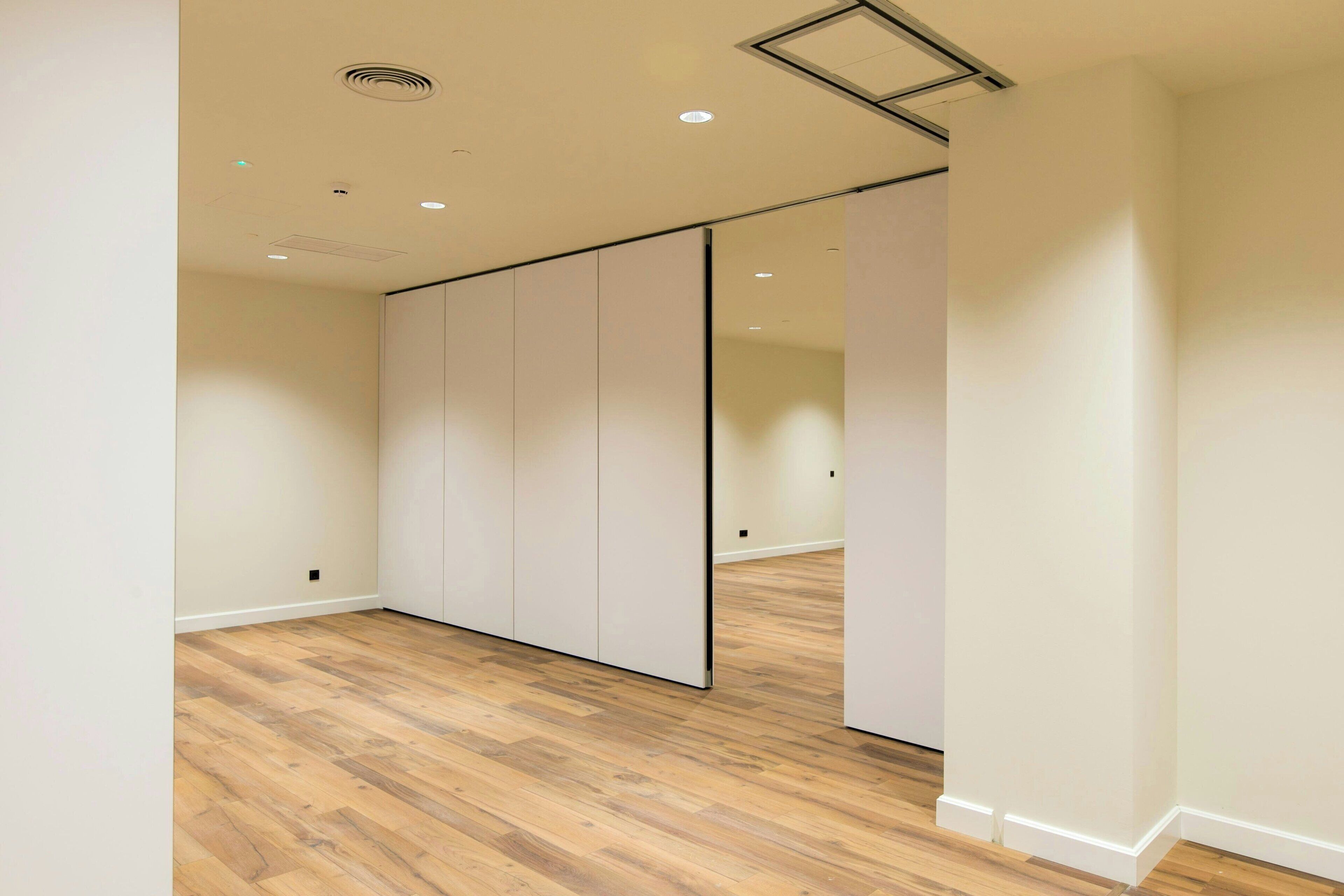 Une pièce dotée d’un plancher en bois, d’une porte coulissante et de spots encastrés au plafond.
