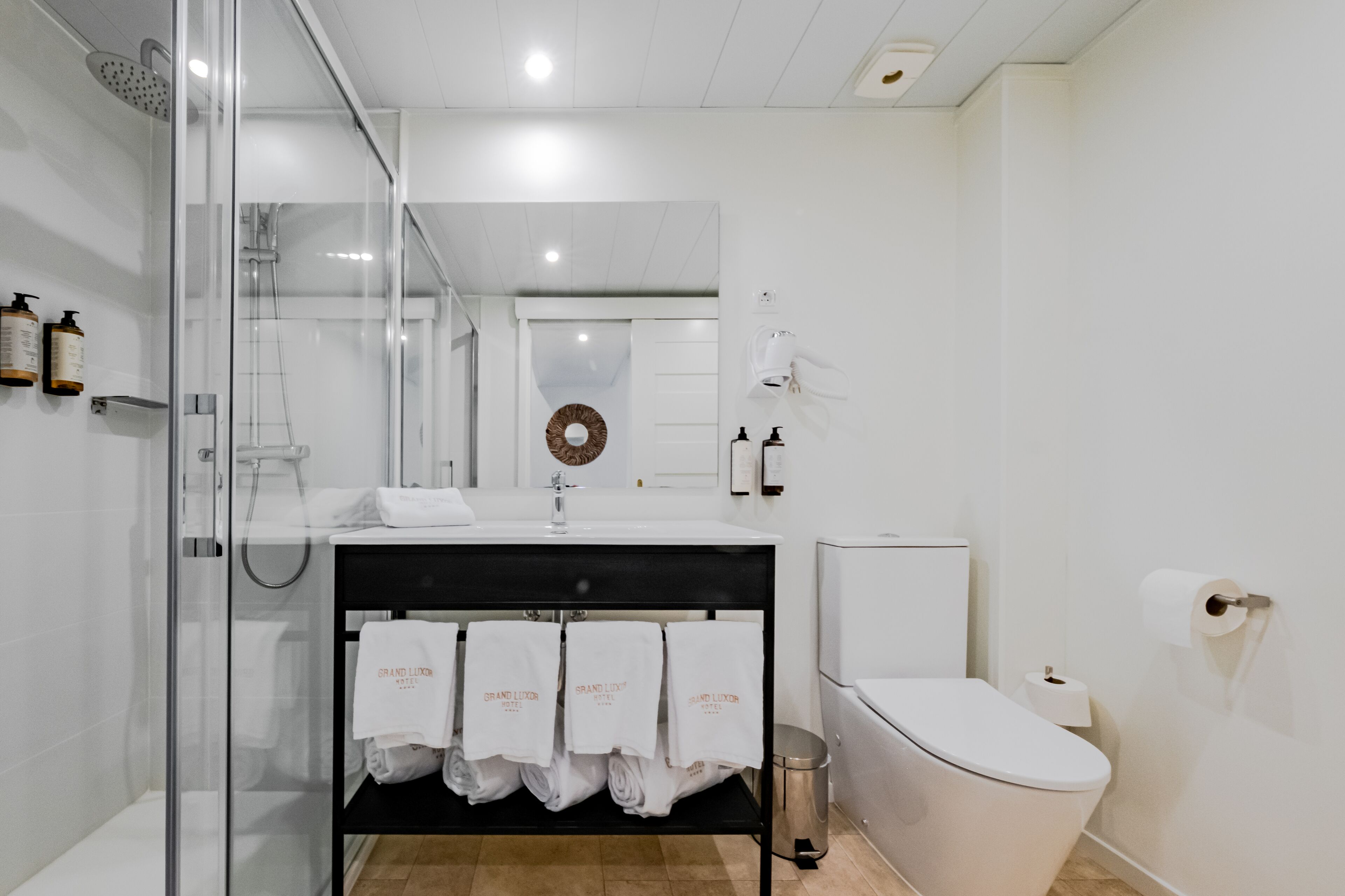 A modern bathroom with a glass-enclosed shower, a white sink with a black countertop, and a toilet.