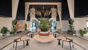 Un hall amplio con una zona de estar central, plantas en macetas y un mostrador de recepción.