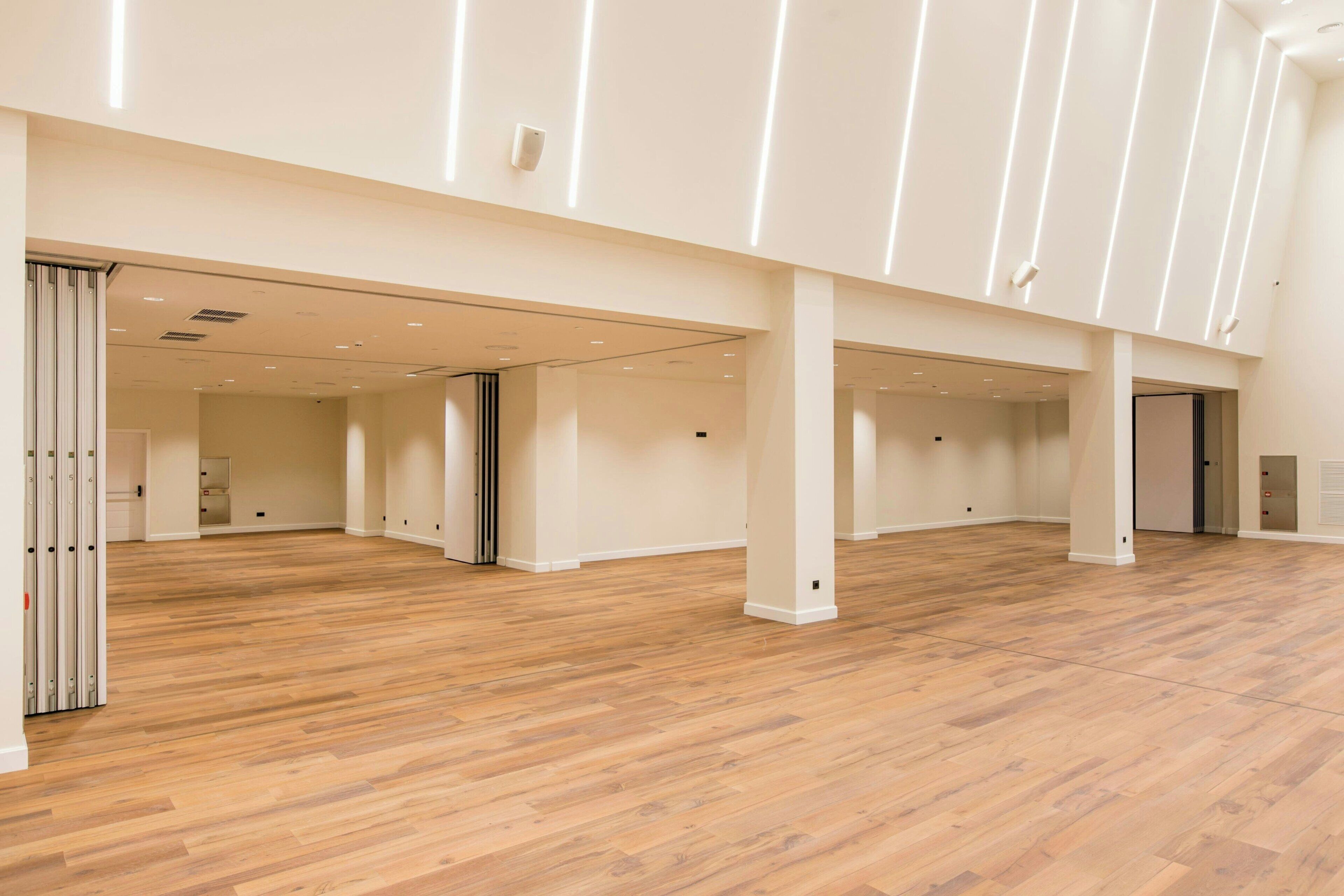 A spacious interior with wooden flooring and white walls, featuring multiple doorways and a central open area.