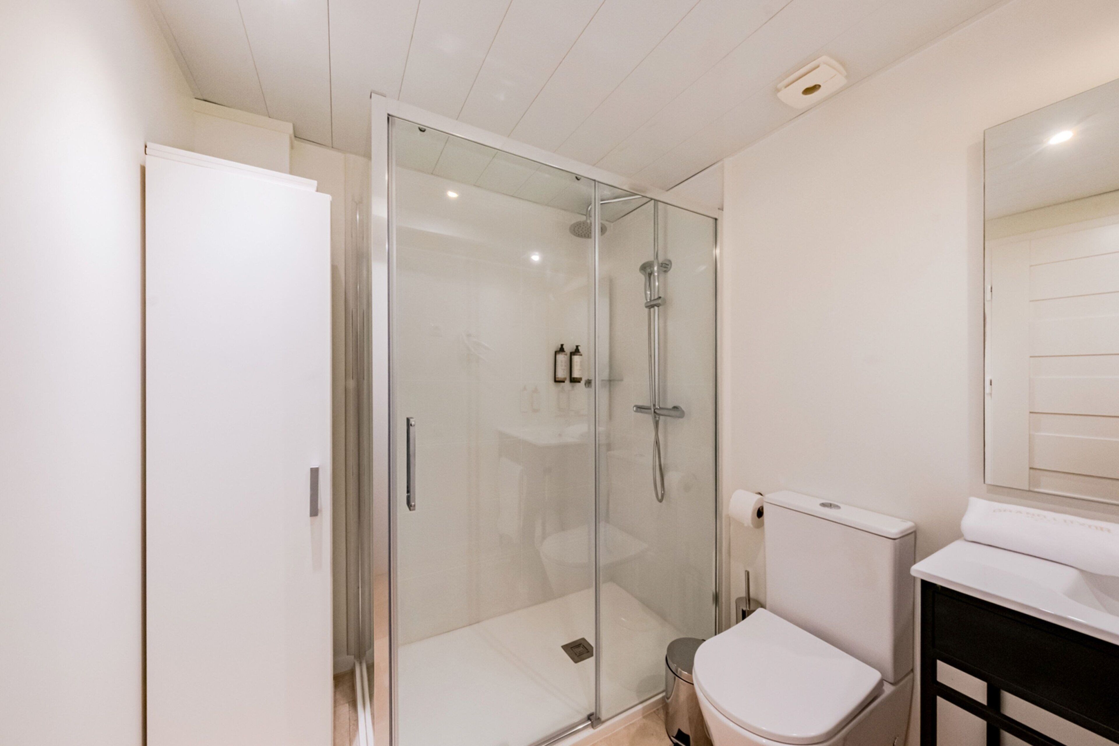 Une salle de bain moderne avec une douche à parois de verre, des toilettes blanches et un lavabo.