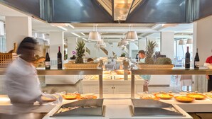 Zona de bufé con diversos alimentos y un chef preparando comida.