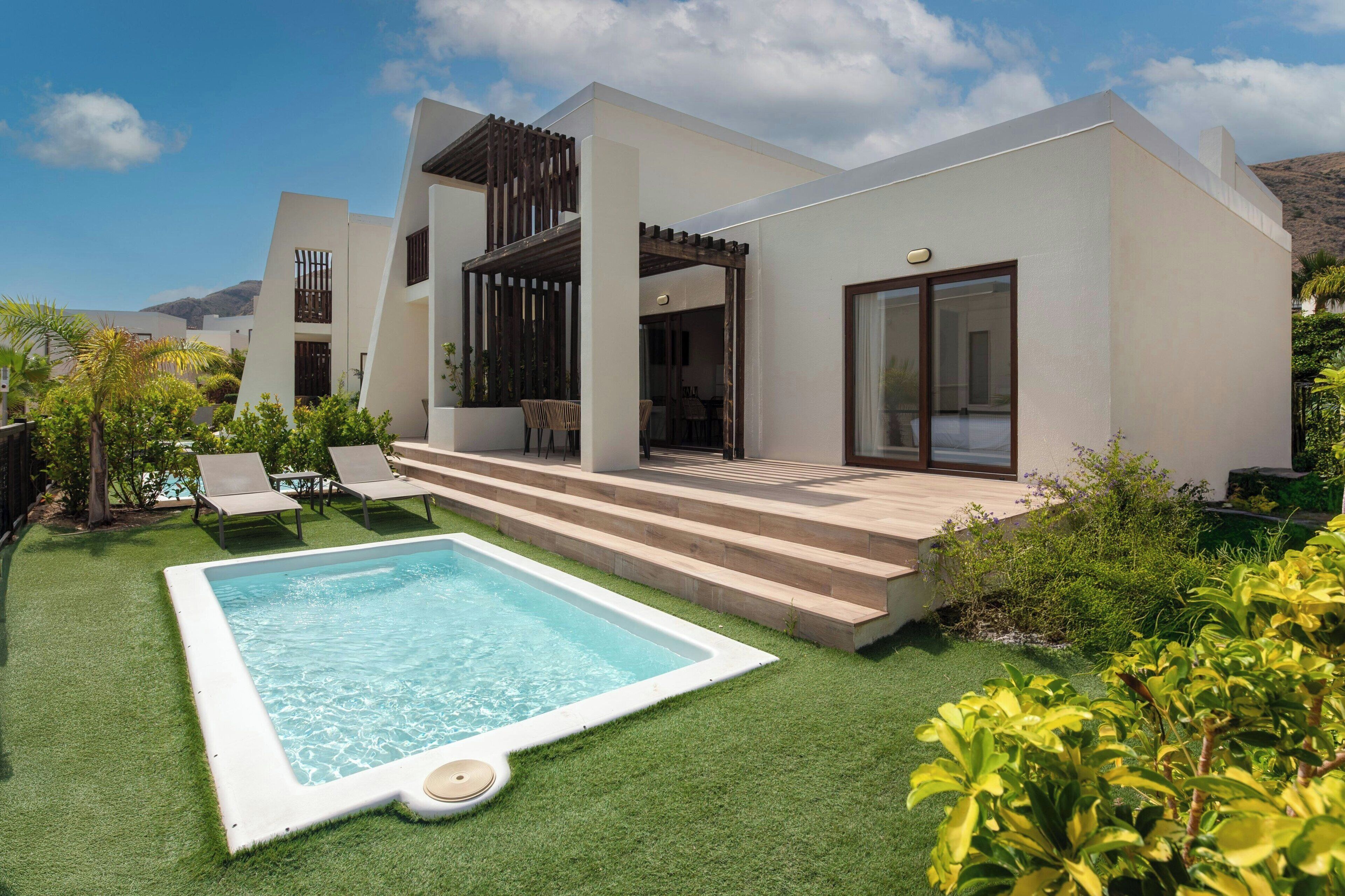 Une maison moderne dotée d’une piscine, d’un espace salon extérieur et d’un patio.
