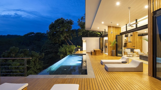 A modern outdoor living area with a pool, wooden deck, and seating. - Luxury modern Villa North Santa Teresa Walk To Surf (Santa Teresa Beach)