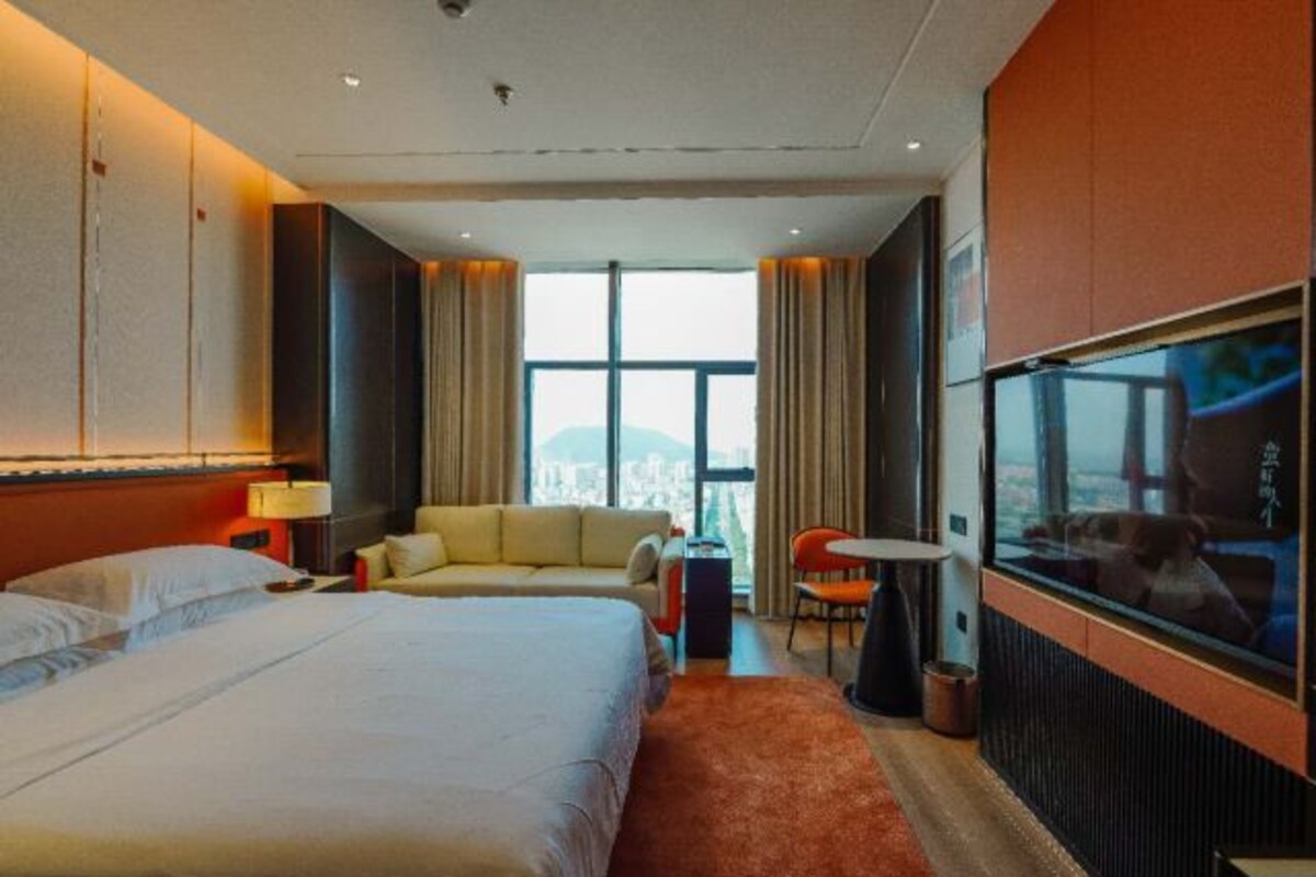 Una habitación de hotel con dos camas, un sofá, una mesa de comedor y un televisor.
