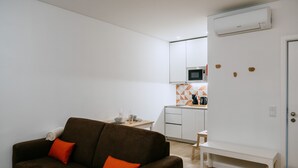 Un espace de vie compact comprenant un canapé marron, une petite table à manger et un coin cuisine.