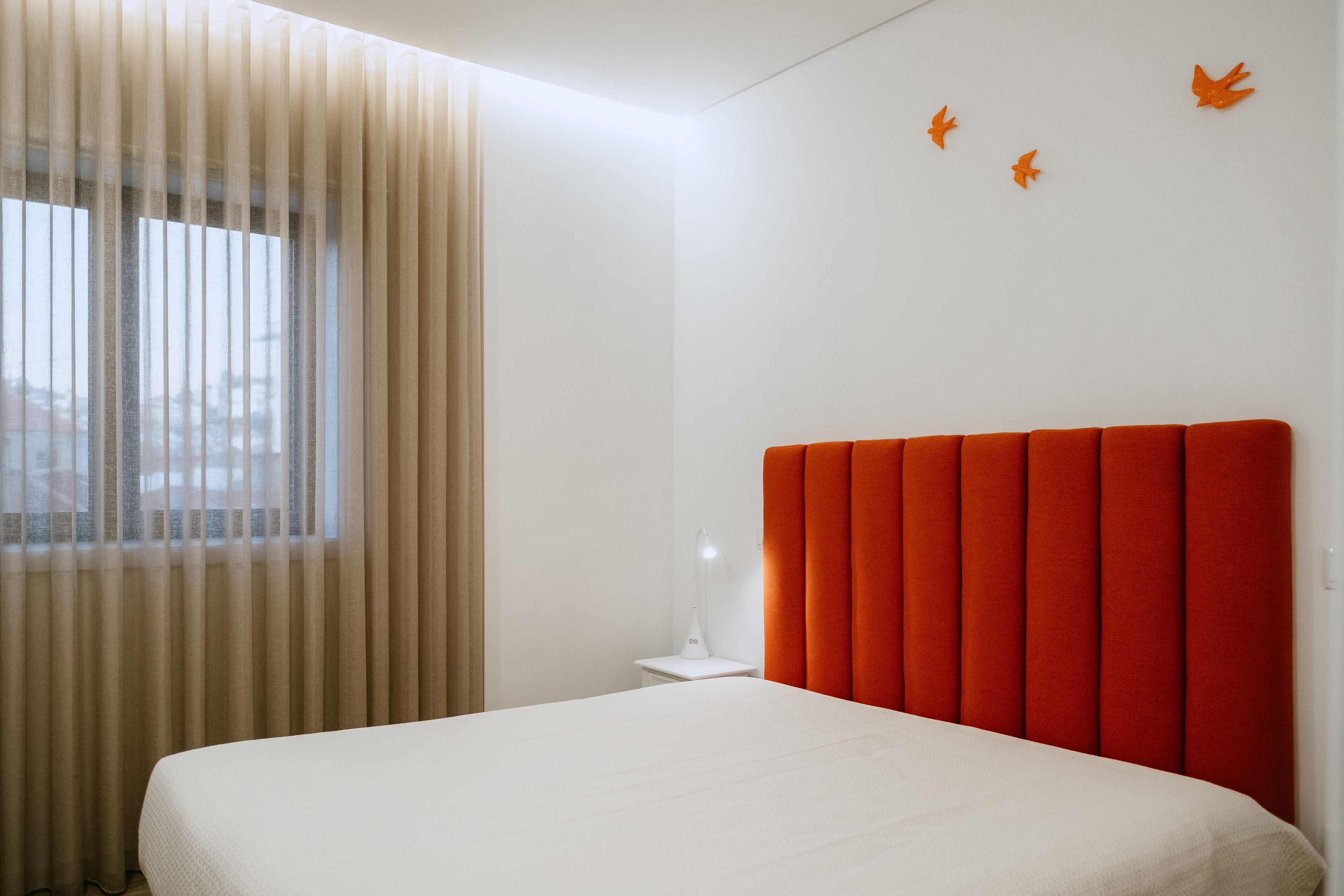 A bedroom with a bed, a nightstand, a lamp, and a window with curtains.