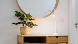 Un bureau en bois avec un miroir, une lampe blanche et une plante en pot.