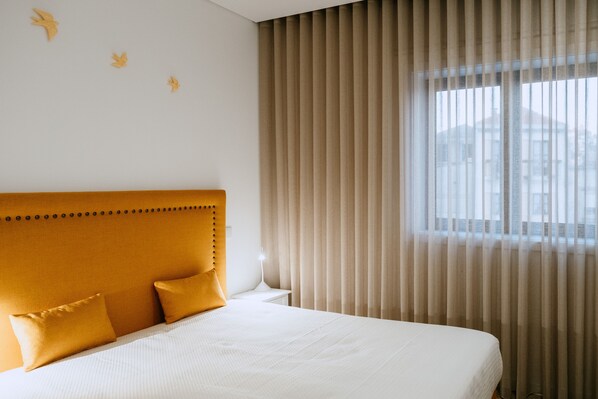 A hotel room with a large bed, a headboard, and a window with curtains.