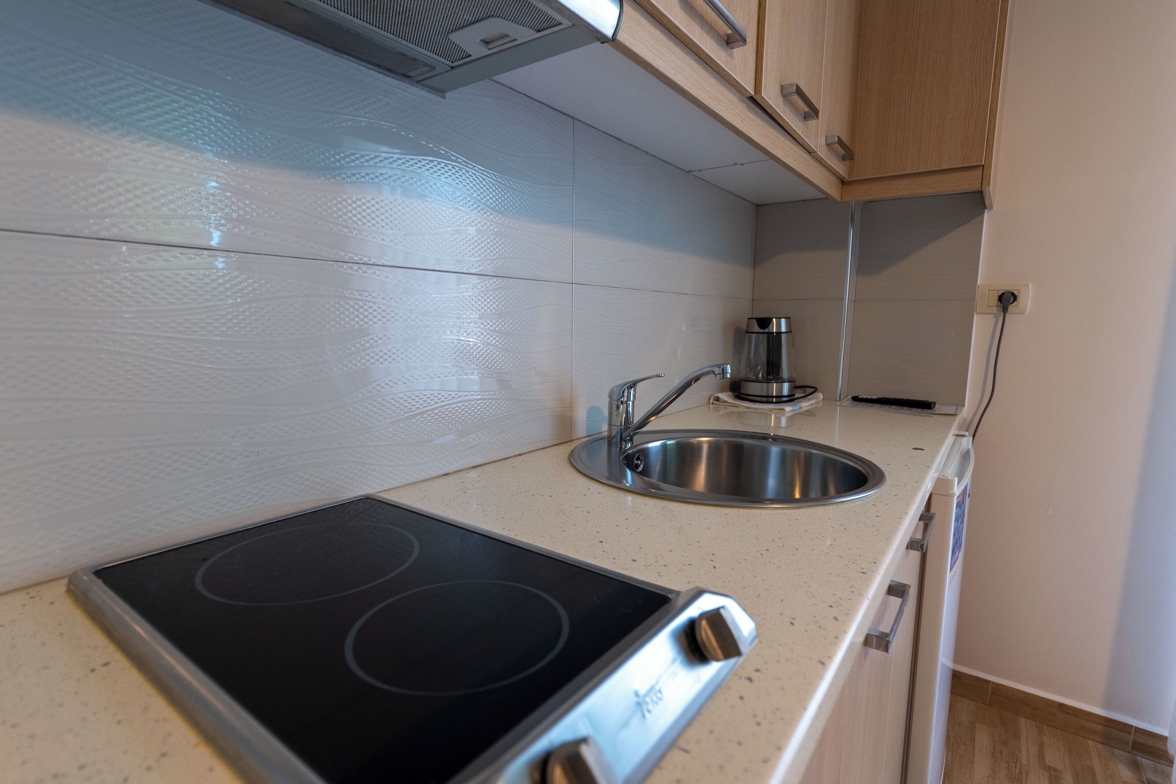 A modern kitchen with a built-in stove, stainless steel sink, and wooden cabinets.