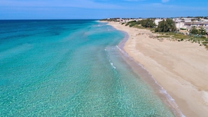 Ein Küstenstrand mit klarem türkisblauem Wasser und einem Sandufer.
