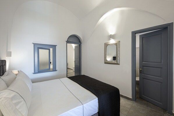 A bedroom with a bed, a mirror, and a door.