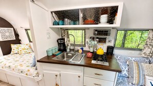 A compact kitchenette with a sink, stove, and storage cabinets. - Lakefront Airstream - Farm Animals - Fish, Swim, Boat, Hike/Bike 5+Miles Trails (Louisa)