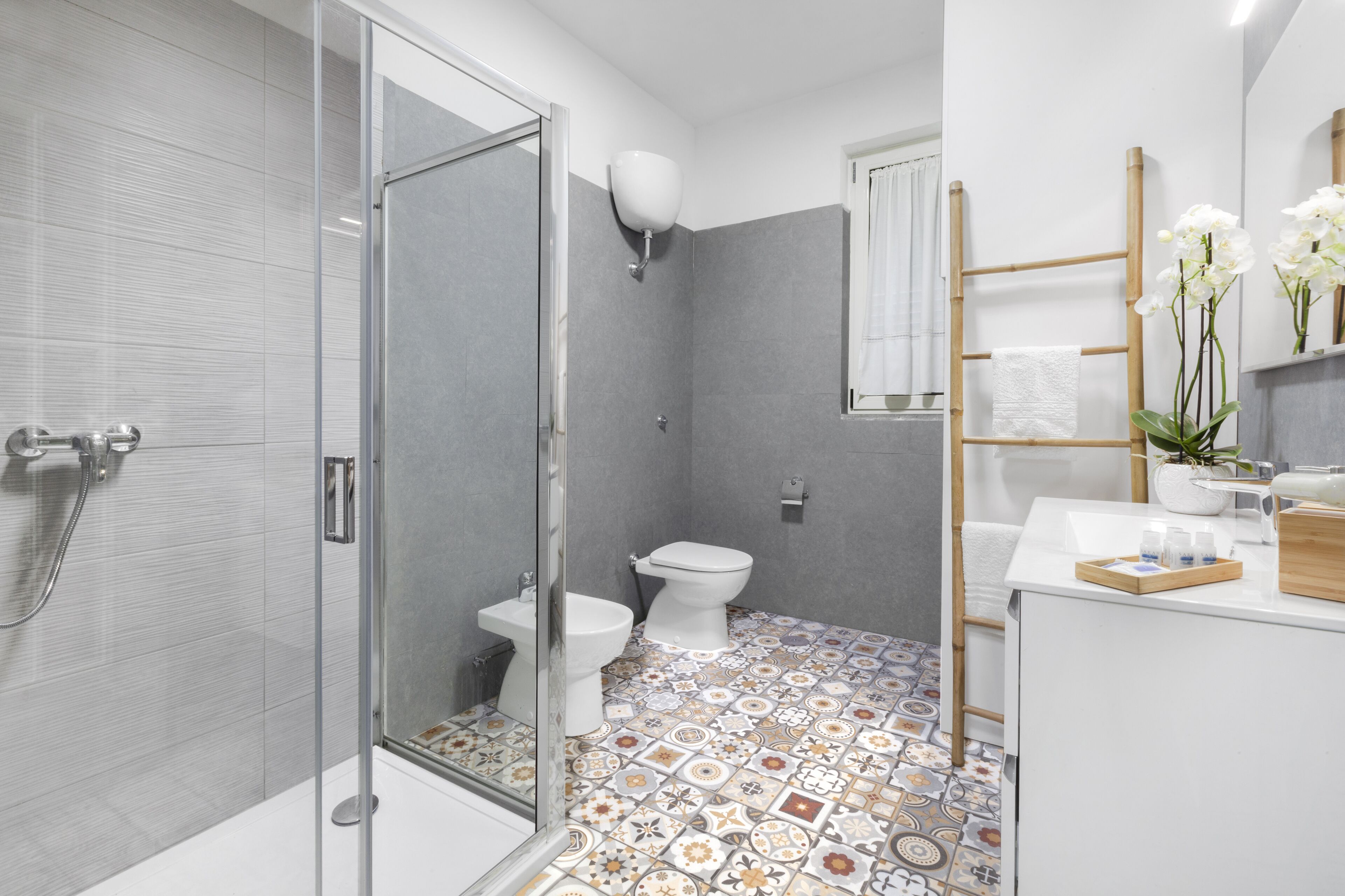 Et moderne badeværelse med brusekabine i glas, toilet og vaskeområde med spejl og håndklædetørrestativ.
