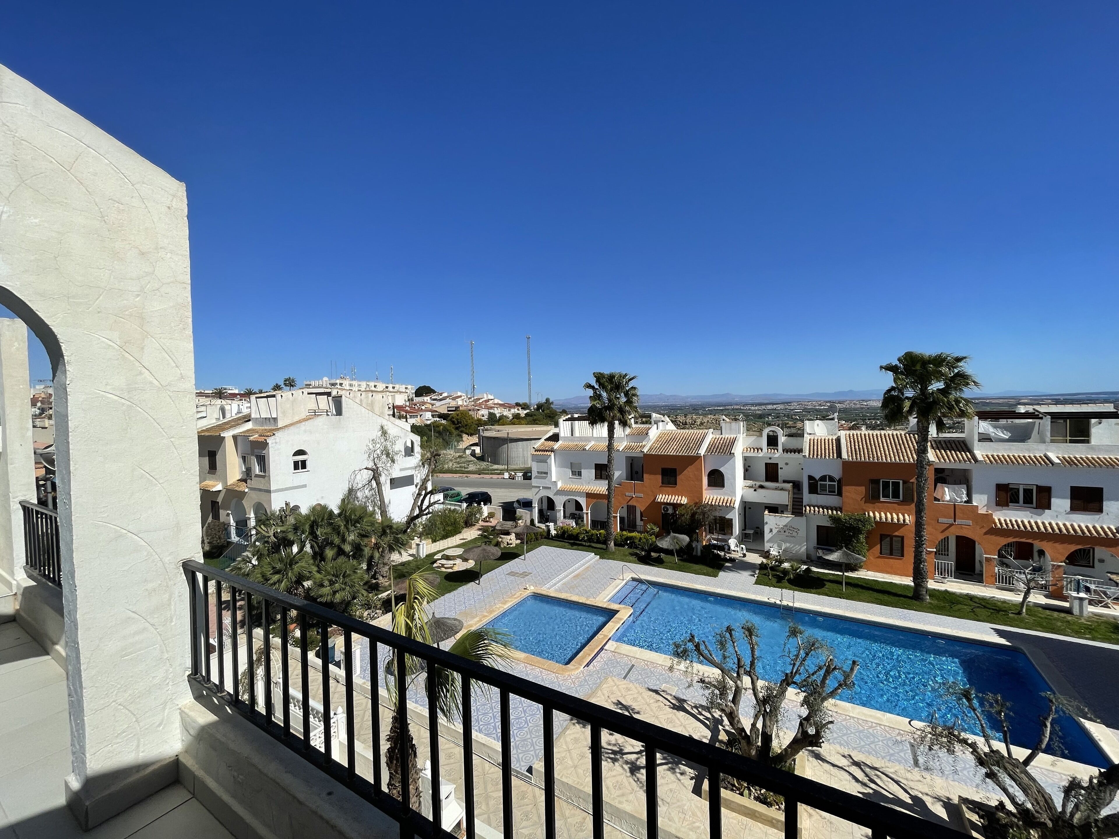 Zona de piscina con vistas despejadas a edificios circundantes y una cadena montañosa distante.