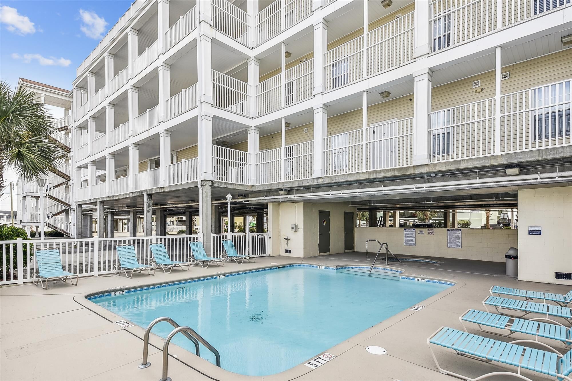 Un hotel de varios pisos con piscina y mobiliario exterior.