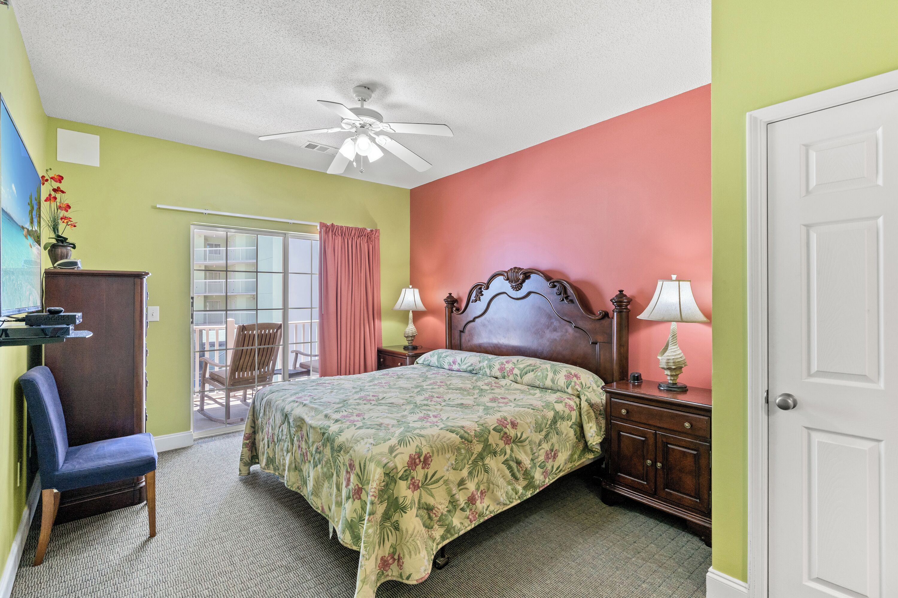 A bedroom with a bed, a chair, a desk, and a door.