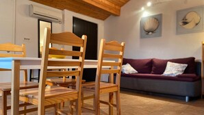 Une table à manger en bois avec des chaises, un canapé violet et un sol carrelé.