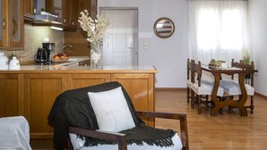 A kitchen with wooden cabinets, a dining area with a wooden table and chairs, and a vase with flowers on the counter. - Sky Corfu City View Loft (Corfu)