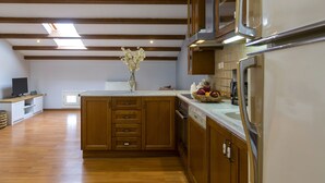 A modern kitchen with wooden cabinets, a central island, and a built-in oven. - Sky Corfu City View Loft (Corfu)