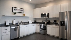 Una cocina moderna con electrodomésticos de acero inoxidable, armarios de madera clara y encimera oscura.
