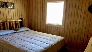 A wooden room with a bed, a window, and a sign that says "GONE HUNTING".