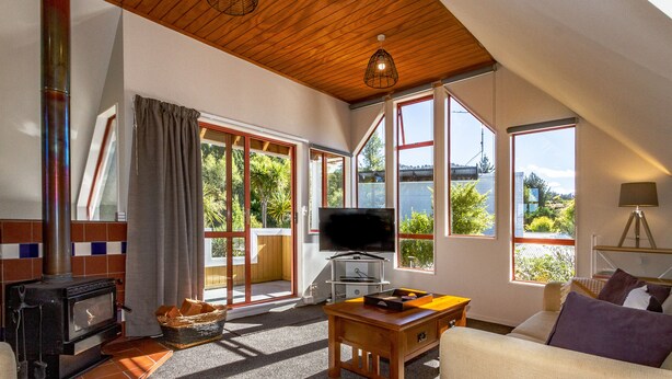 Una sala de estar acogedora con chimenea, televisor y un amplio ventanal con vistas al verdor.