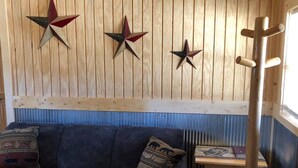 Ett rum med en blå soffa, träpanel på väggarna och tre stjärnformade dekorationer.