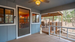 A covered porch with a ceiling fan, a sliding glass door, and a view of the outdoors. - Tall pines cabin with chimney at "Upper Canyon" (Ruidoso)