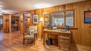 A wooden-paneled room with a dining table, a desk with a lamp, and a framed picture on the wall. - Tall pines cabin with chimney at "Upper Canyon" (Ruidoso)