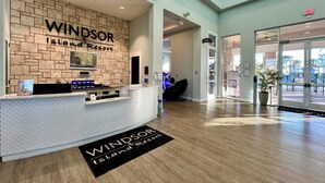 A reception area at Windsor Island Resort with a brick wall, a reception desk, and a view of the outside.