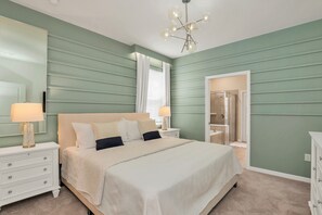 Un dormitorio con cama, mesitas de noche, un espejo y un vestidor.