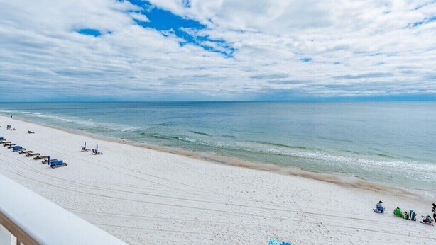 Una spiaggia con sabbia bianca, cielo azzurro limpido e mare calmo.