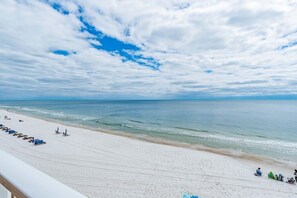 Una spiaggia con sabbia bianca, cielo azzurro limpido e mare calmo.