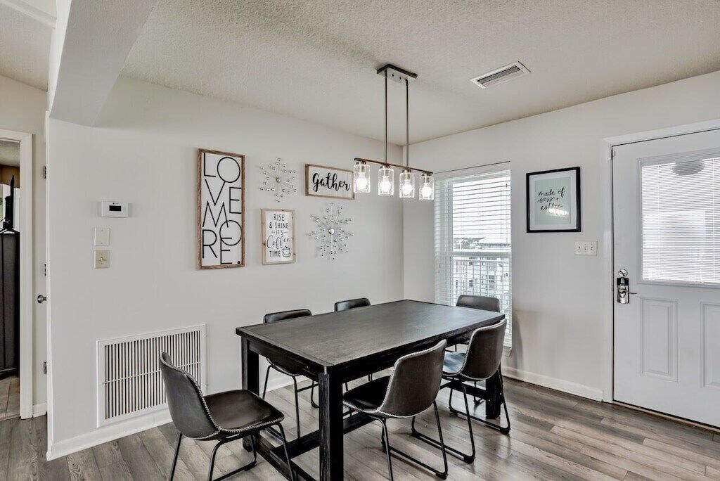 Un espace repas comprenant une table rectangulaire, six chaises et un luminaire suspendu.