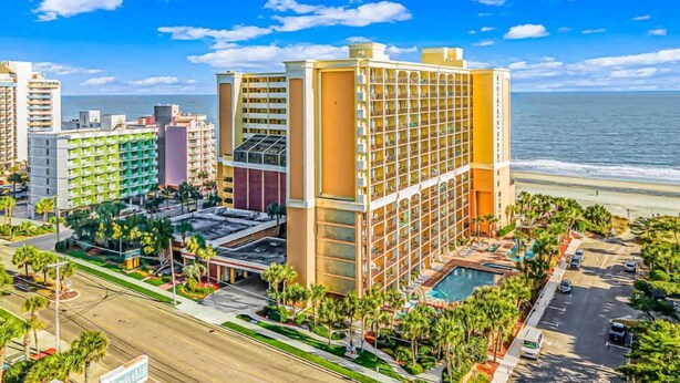 Ein Hotel mit mehreren Etagen, einem Pool und Blick auf den Strand.