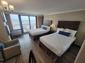 Une chambre d’hôtel avec deux lits, un bureau, une chaise et un balcon avec vue.