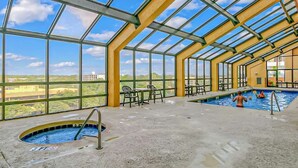 Ein Hallenbad mit Glasdach, mehreren Bahnen und Liegestühlen rund um den Pool.