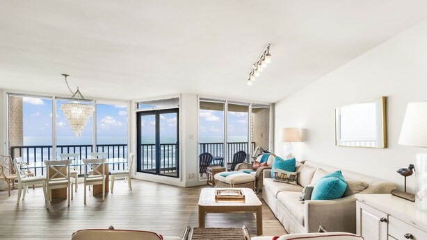 Ein geräumiges Wohnzimmer mit Meerblick, möbliert mit Korbstühlen, einem Sofa und einem Couchtisch.