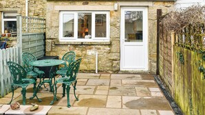 A stone house with a small patio, a white door, and a window overlooking the garden. - 2 bedroom accommodation in Clapham, near Ingleton (Clapham, near Ingleton)